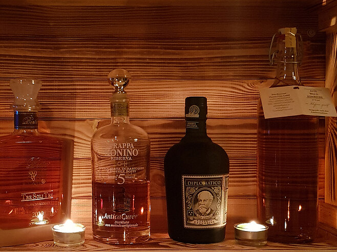 Hochwertige Spirituosen und Liköre stilvoll präsentiert in einer beleuchteten Holznische der Hotelbar in Ischgl.