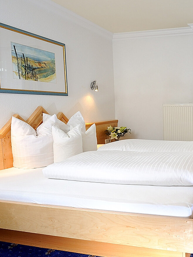 Hotelzimmer mit Doppelbett, Tisch und Stuhl, Fernseher an der Wand und Balkonfenster mit Vorhängen