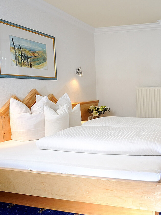 Hotelzimmer mit Doppelbett, Tisch und Stuhl, Fernseher an der Wand und Balkonfenster mit Vorhängen