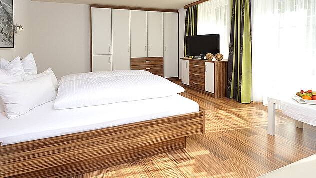 Doppelzimmer Deluxe im Hotel Garni Valülla Ischgl mit großem Bett, Holzboden und Schrankwand