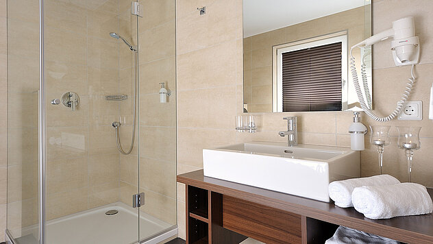Bad im Einzelzimmer Deluxe mit Glasdusche, Aufsatzwaschbecken und Föhn im Hotel Garni Valülla