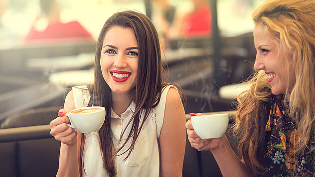 Zwei Frauen genießen Kaffee in gemütlicher Atmosphäre auf einer Sonnenterrasse in Ischgl – entspannter Moment im Skiurlaub.